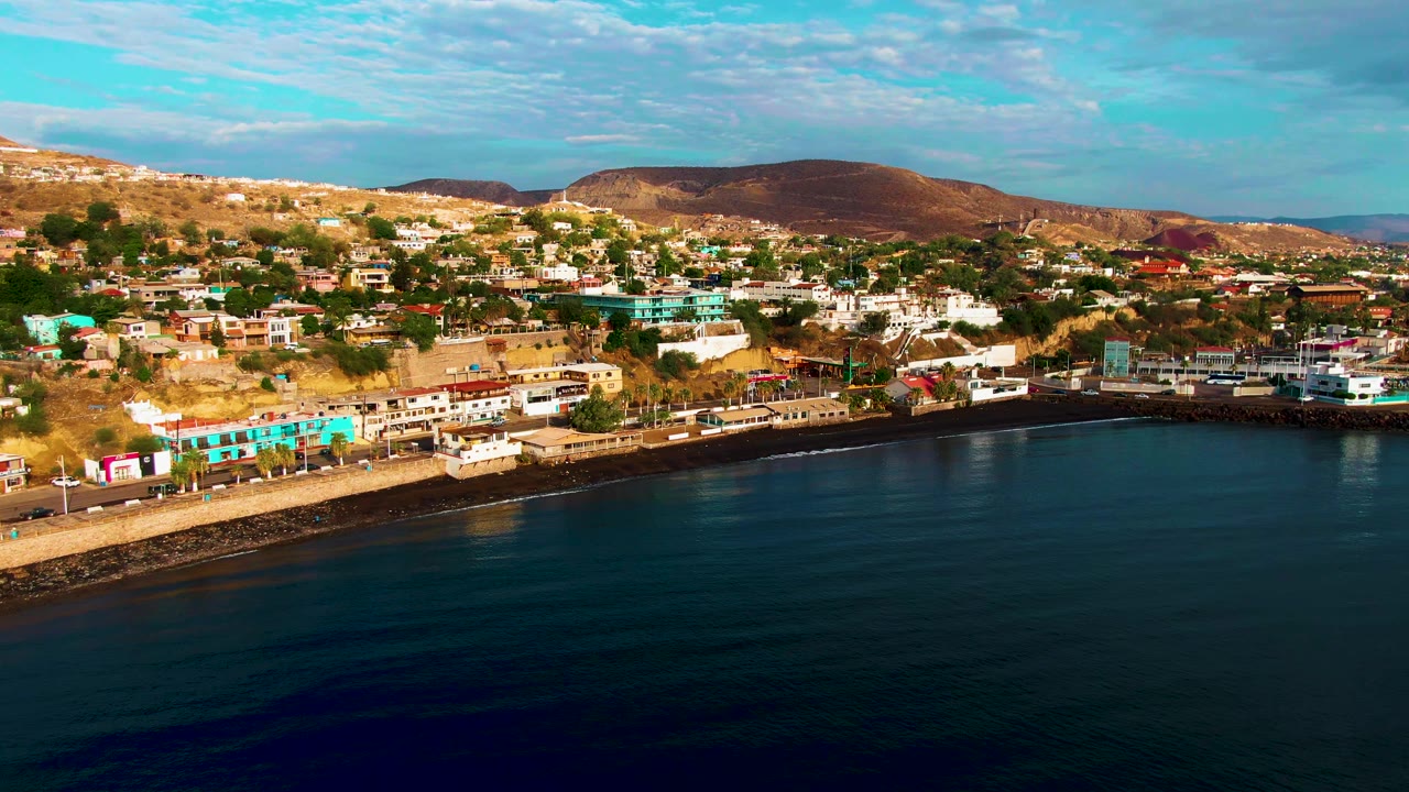 Offshore aerial view of Santa Rosalia shoreline, hillside homes, and calm water.