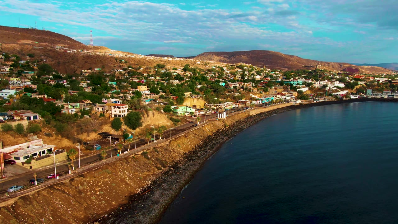 Oceanfront road below hillside houses in dry coastal terrain