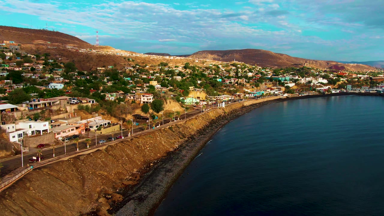 Curving shoreline road with hillside homes and ocean to the right.
