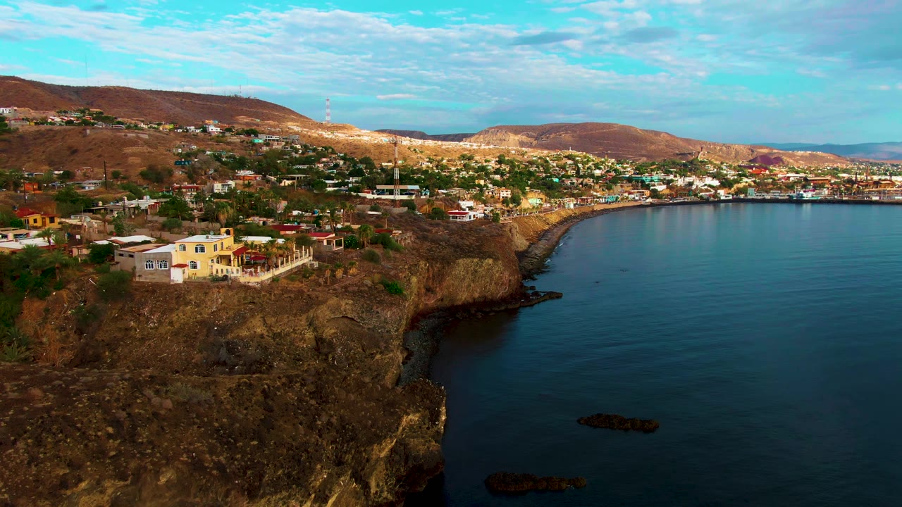 Santa Rosalia's rocky bluff dominates the foreground while clustered buildings and dry hills stretch across the horizon, with no visible people.