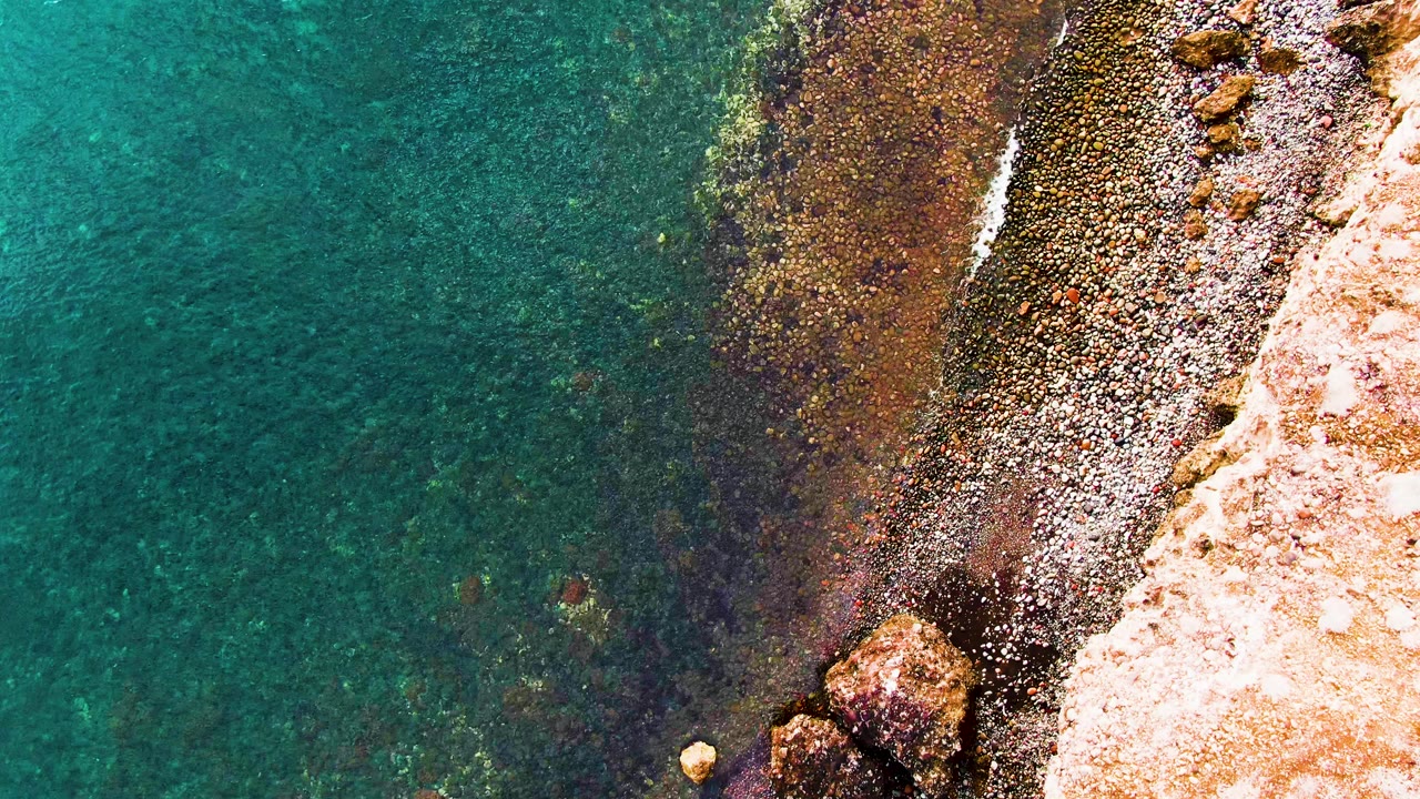 Rocky shoreline and transparent water with the coast running diagonally through frame.