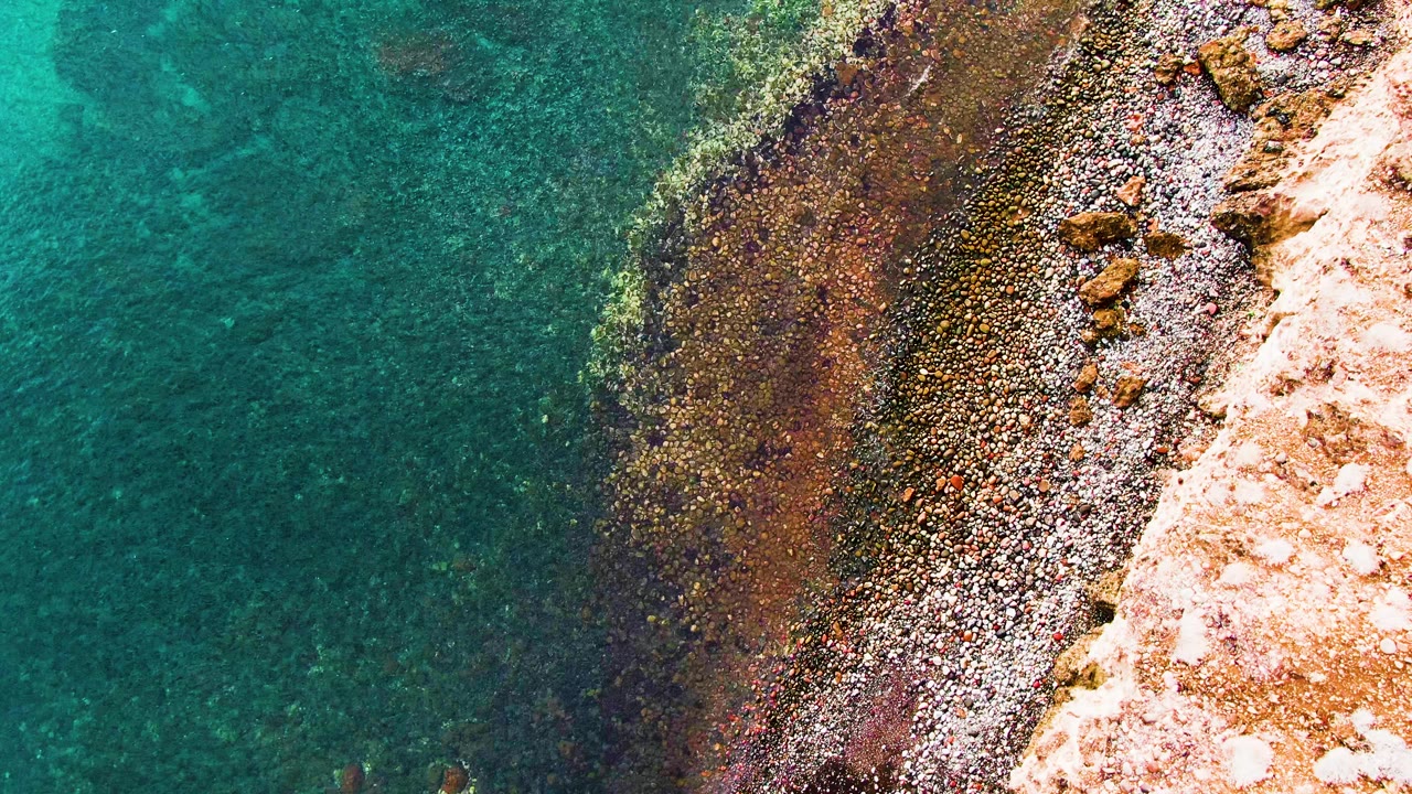 Clear water and pebble shore seen from above.