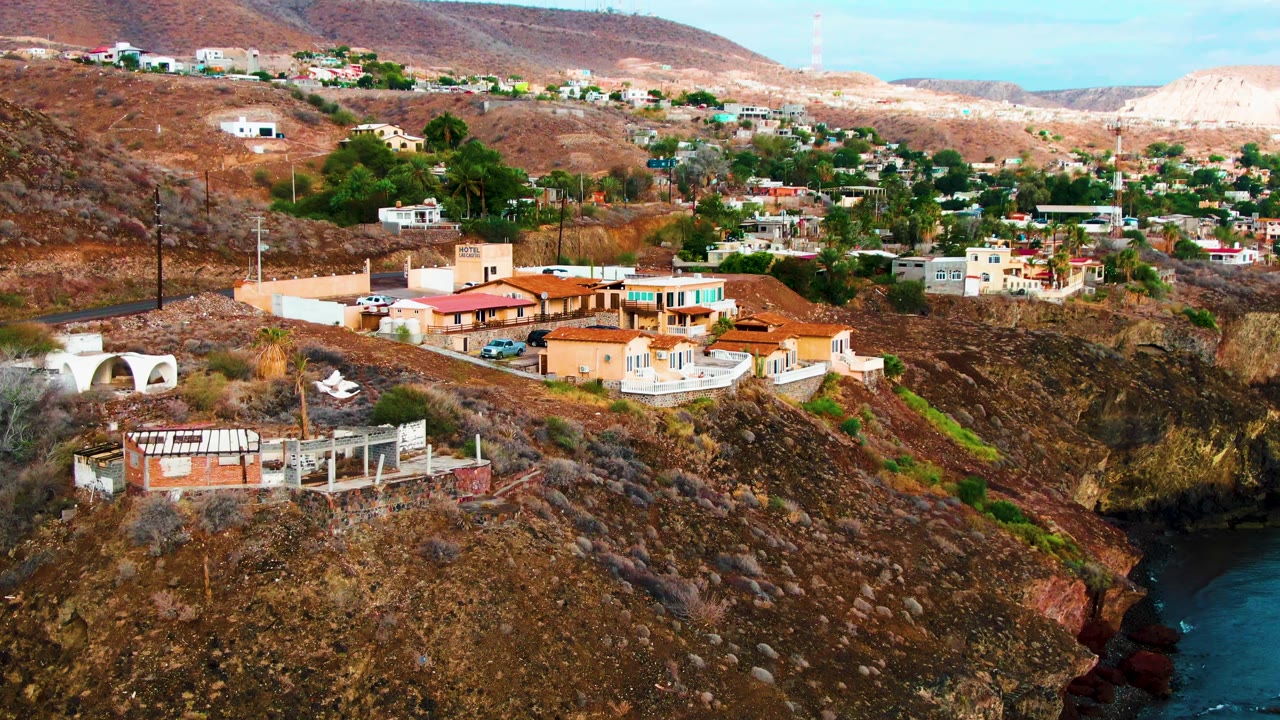 Elevated Santa Rosalia view with homes spread across a brown hillside, an unfinished structure in the lower foreground, and no visible people.