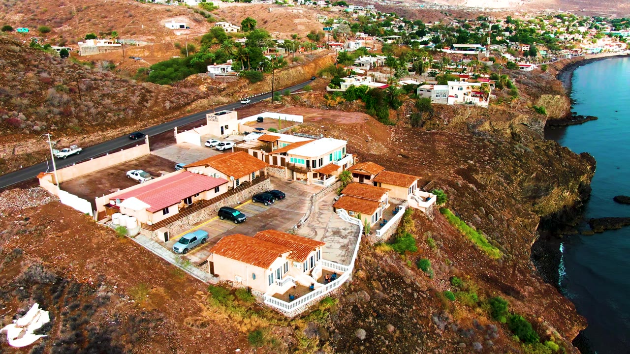 Aerial frame of roadside buildings and parking lot on dry coastal slope.