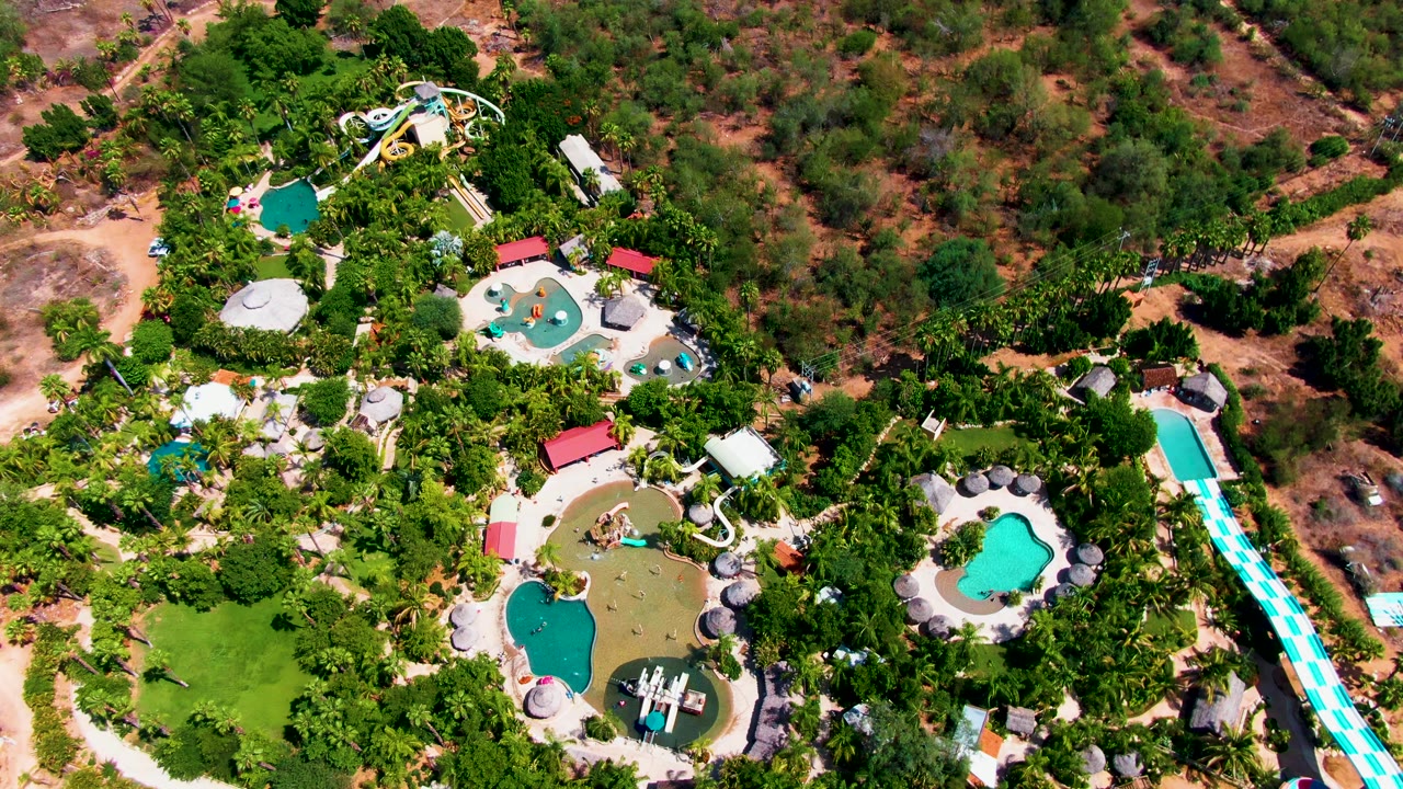 Drone view of a landscaped water park with pools and slides.