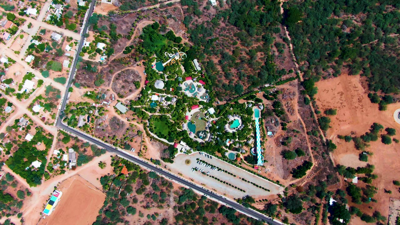 Overhead road and resort pools surrounded by trees and dirt.
