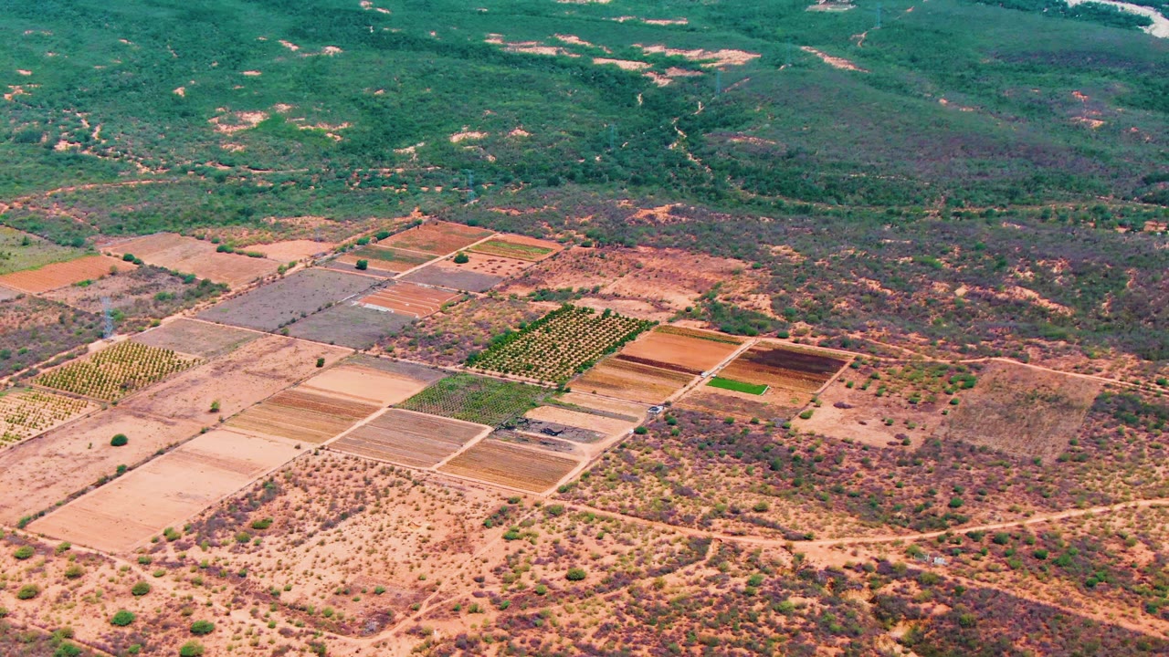 Aerial farmland grid with dry terrain and river beyond