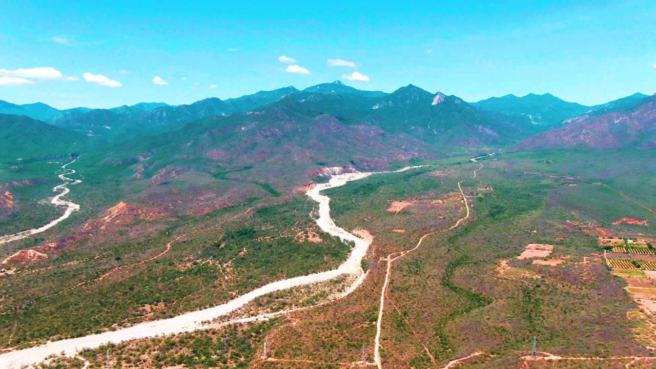 Aerial view of dry valley terrain with winding river and tracks