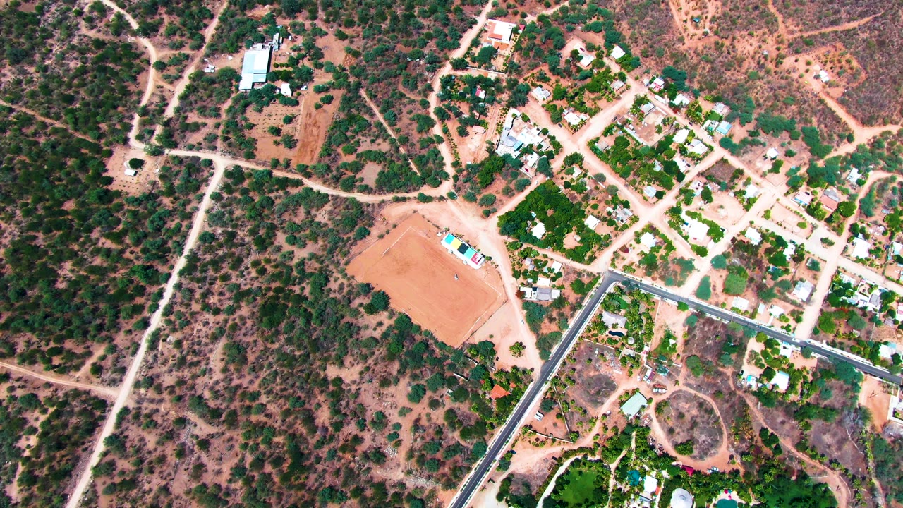 Overhead view of a residential dirt lot, roads, houses, and dry vegetation.