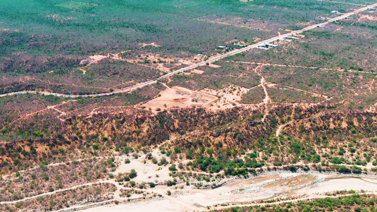 Aerial view of a road crossing dry scrubland above a hillside.