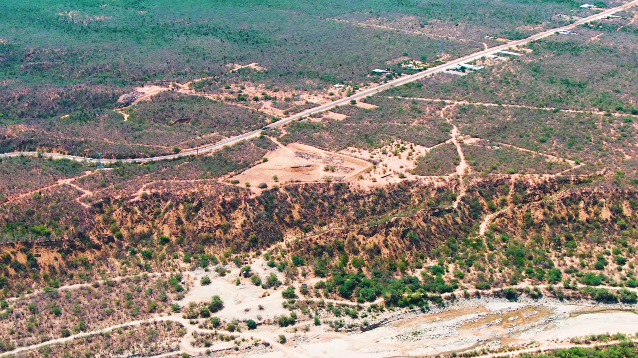 Aerial frame from Caduano, Baja California Sur with the road cutting diagonally through scrubland above a dry eroded hillside and no visible people.