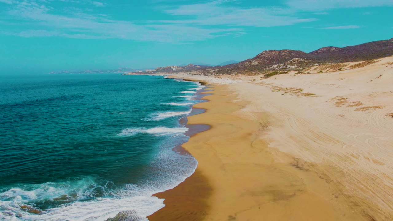 White surf bands curve along a golden beach beside turquoise water