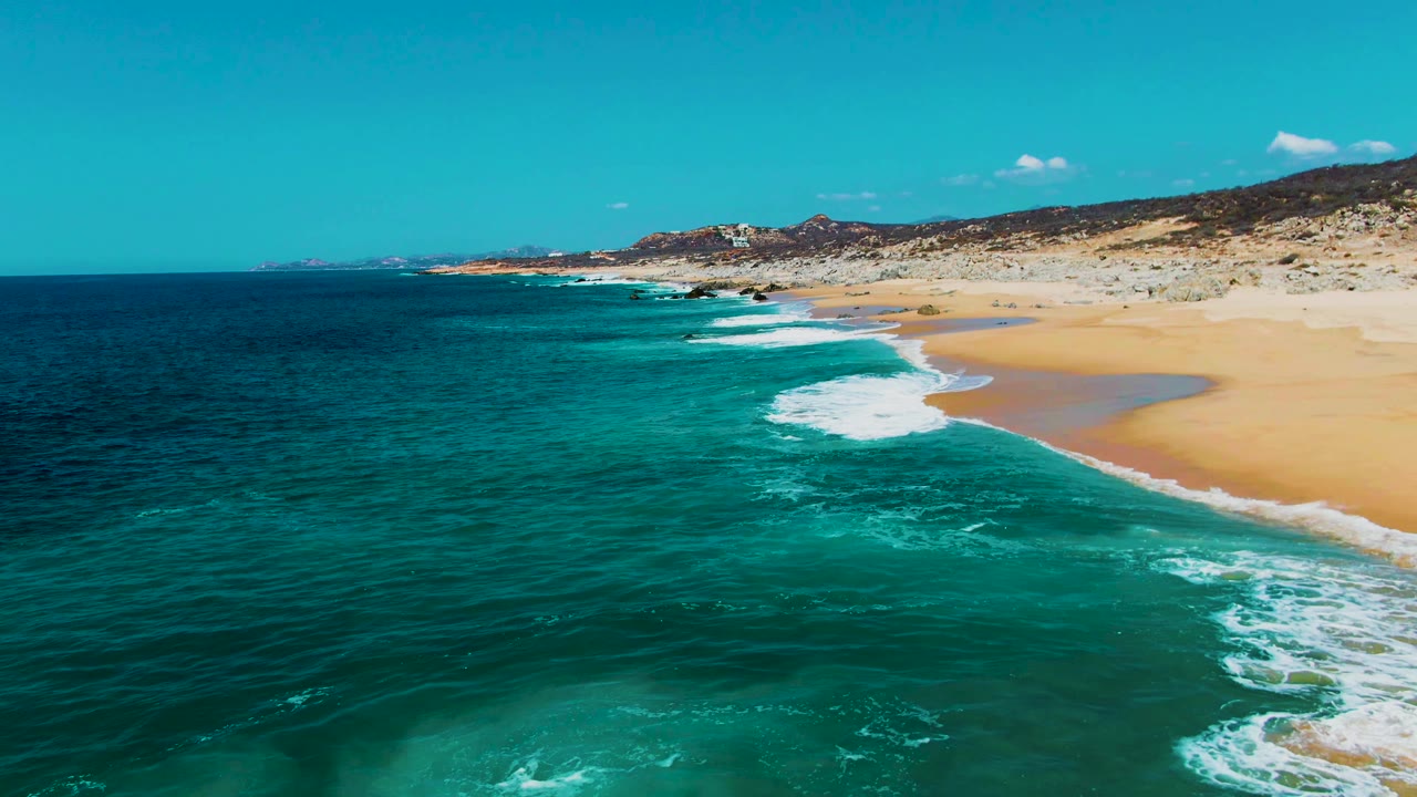Aerial view of turquoise surf approaching a sandy beach