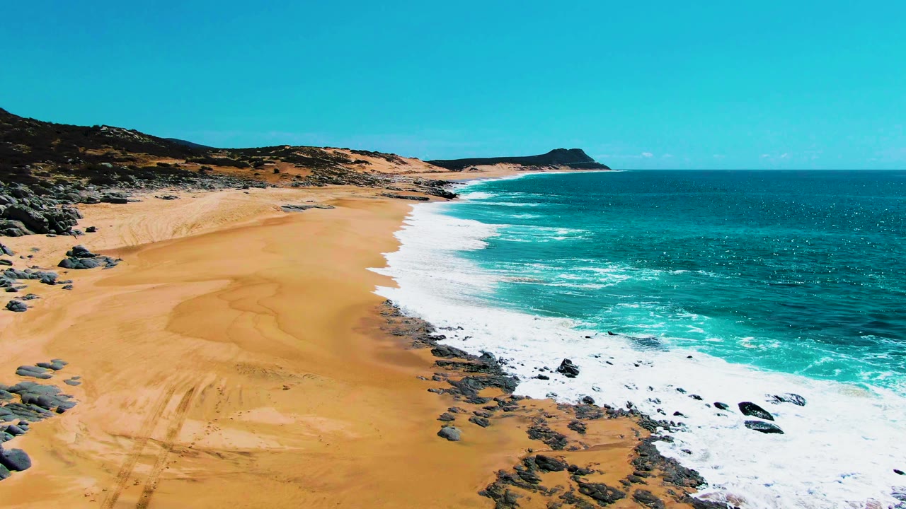 Elevated shoreline view with beach, rocks, and white surf