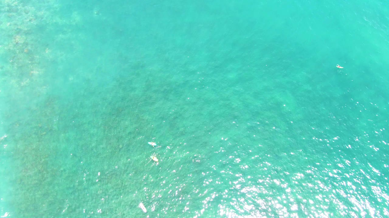 Aerial turquoise sea with scattered swimmers and rippled sunlight
