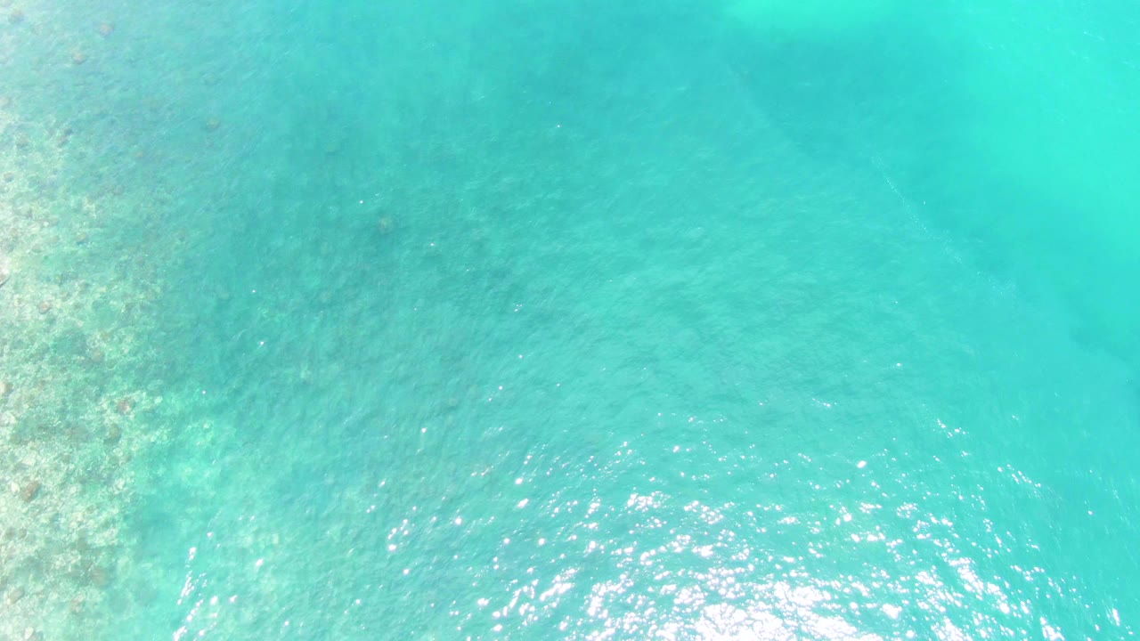 Clear turquoise water with coral texture along the left edge