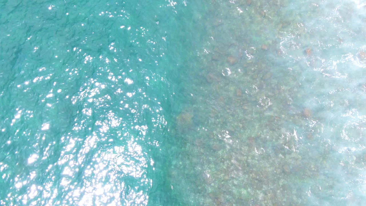 At Buzzards Beach in Baja California Sur, bright sun glints scatter across turquoise water while the seabed is faint beneath the ripples, with no visible people.