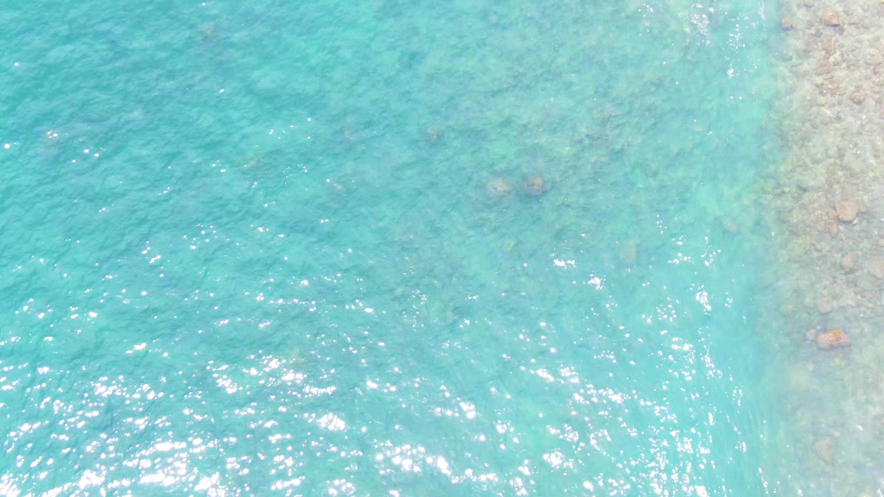 Clear blue-green water with faint rocks below