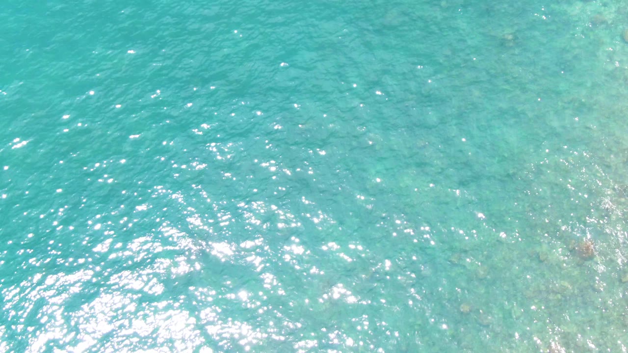 Overhead view of clear turquoise water at Buzzards Beach, East Cape, Baja California Sur, with faint seafloor texture and no visible people.