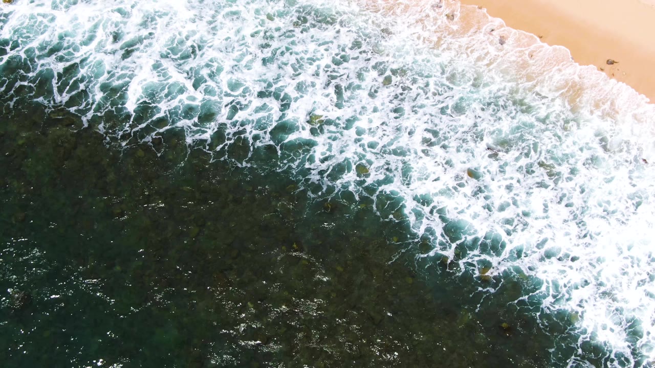 Breaking surf reaches a sandy beach edge