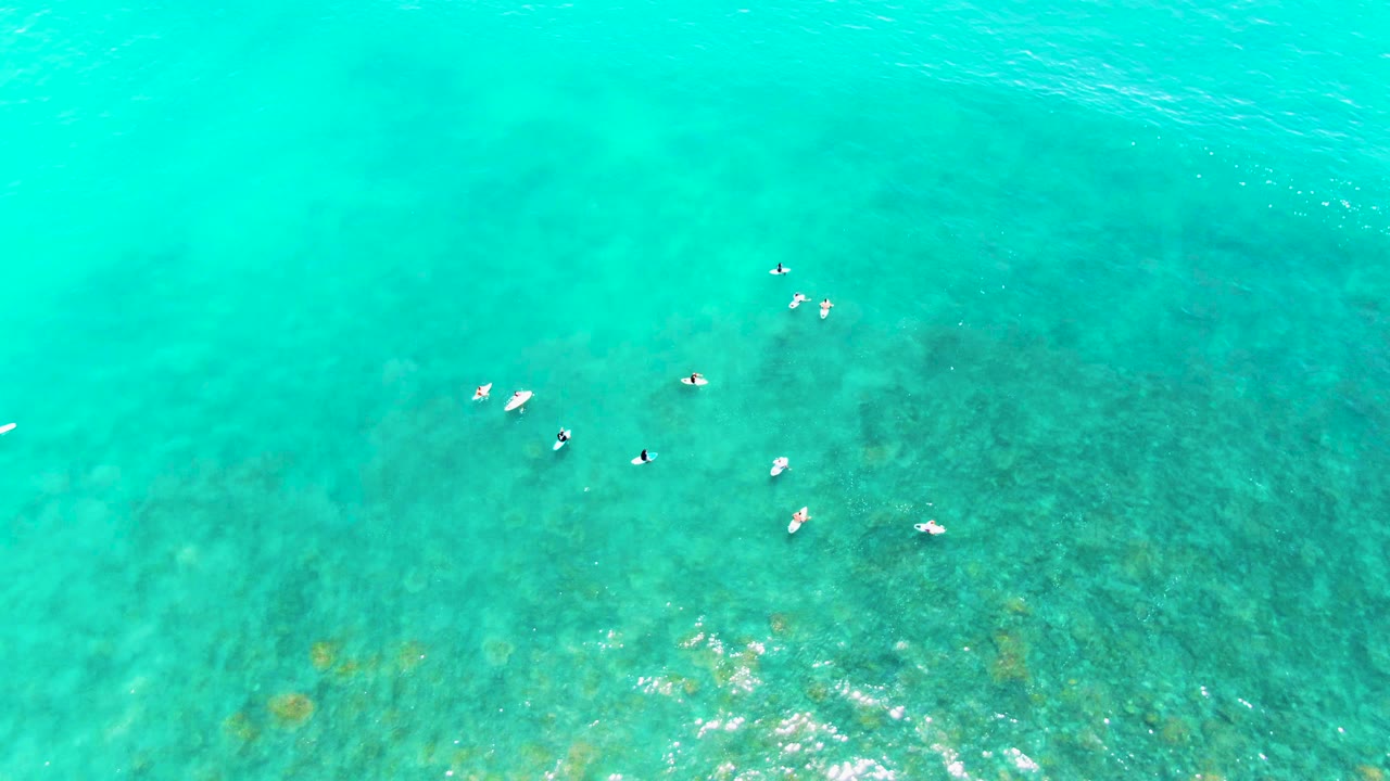 Small swimmers floating over shallow blue-green water.