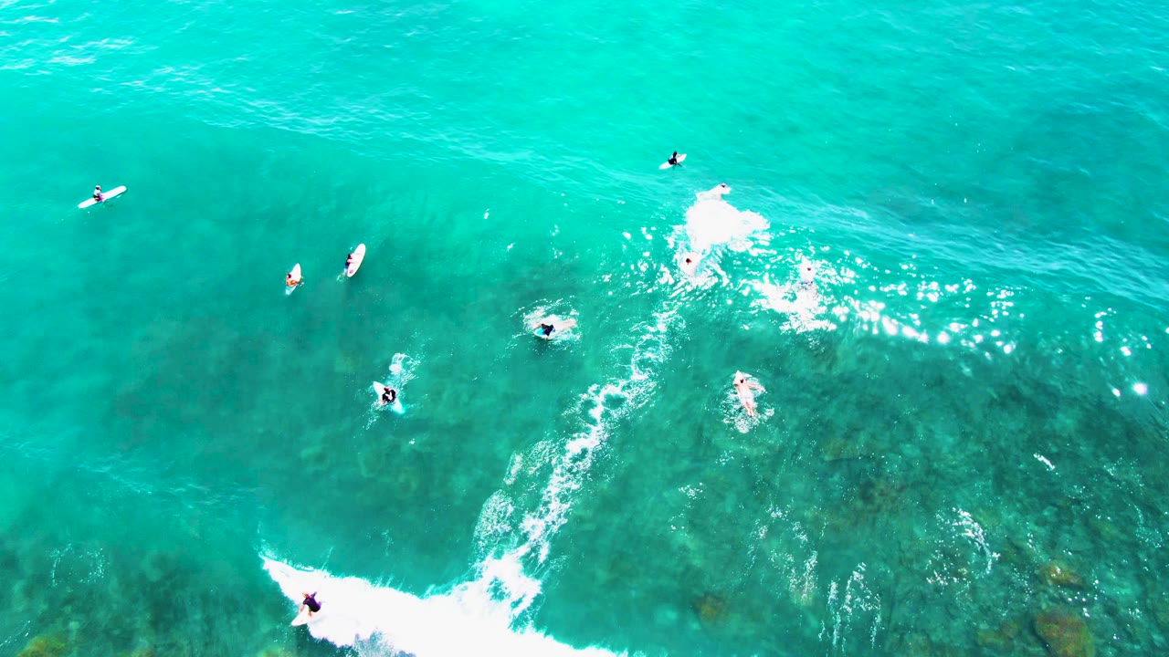 Aerial view of surfers and a diagonal whitewater line.