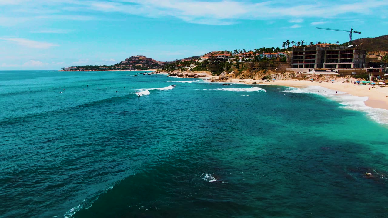 At 0:02, the Punta Buzzards shoreline remains on the right while white surf breaks across the turquoise water and the construction crane stands above the beach.