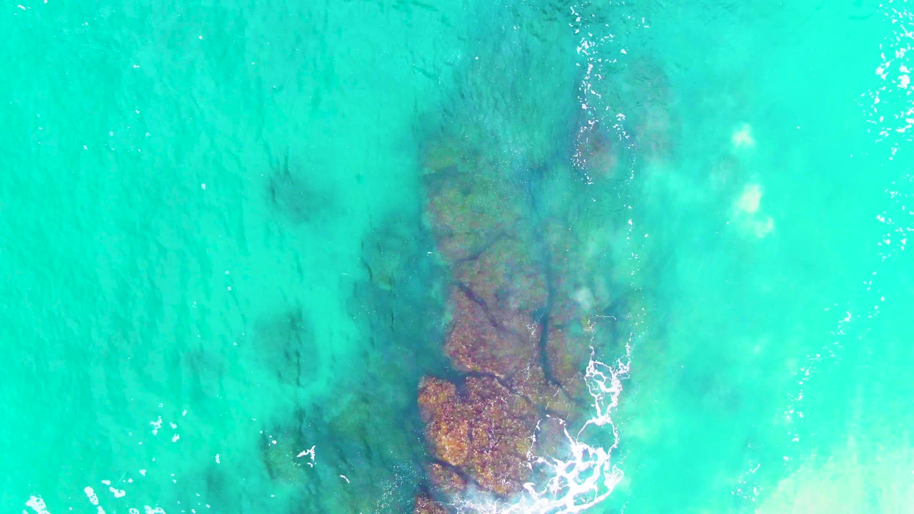 Clear blue-green water with rocky seabed below