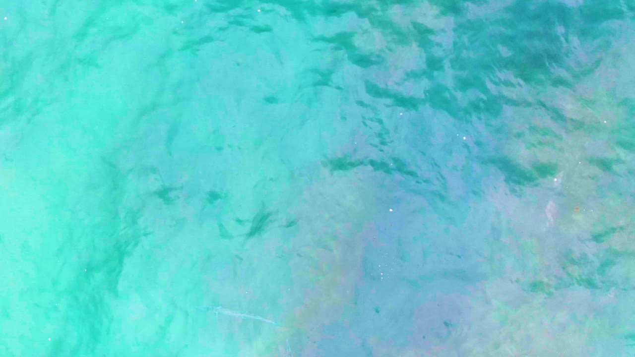 Overhead turquoise water with faint fish and seabed texture.