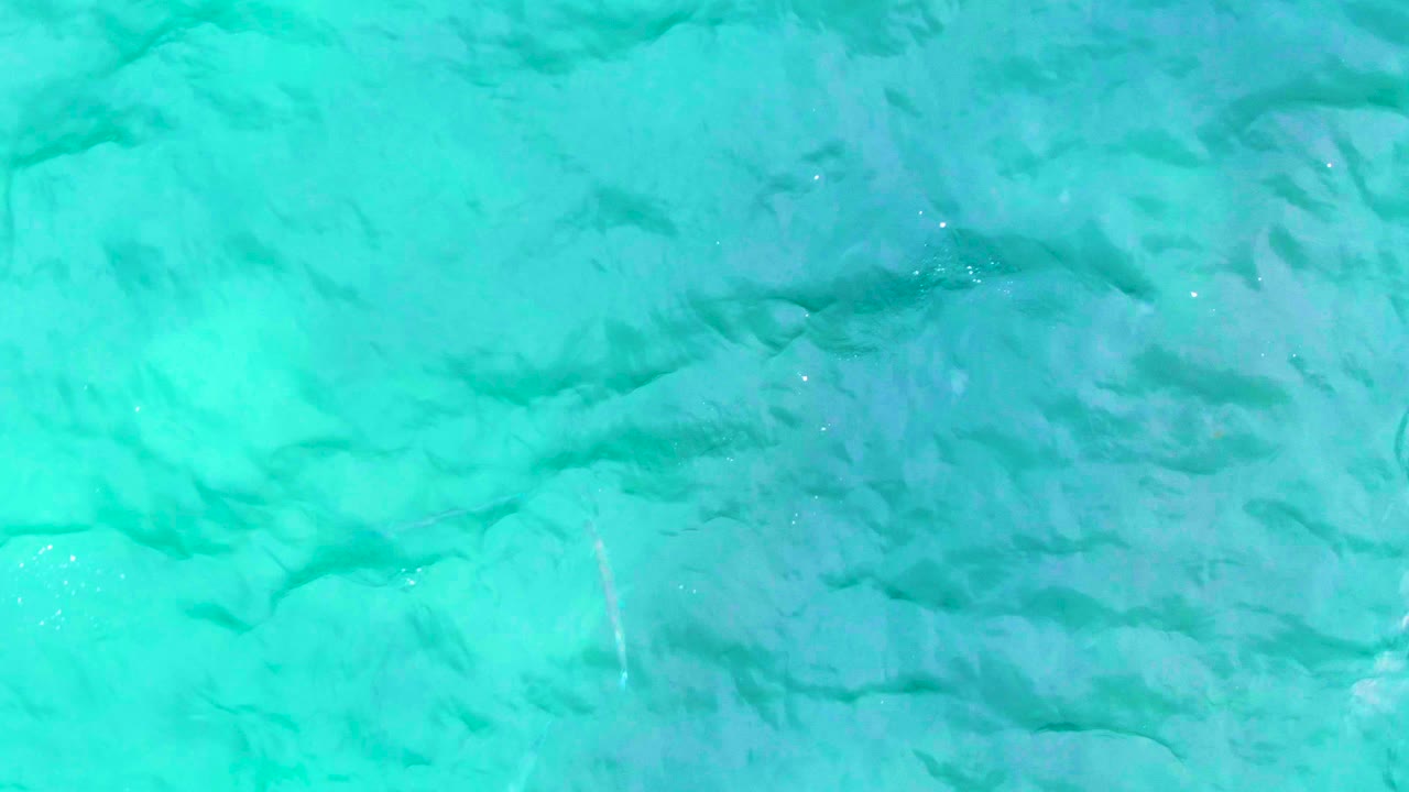 Blue-green ocean water at Punta Buzzards shows broader ripples and faint subsurface shading, with no visible people.