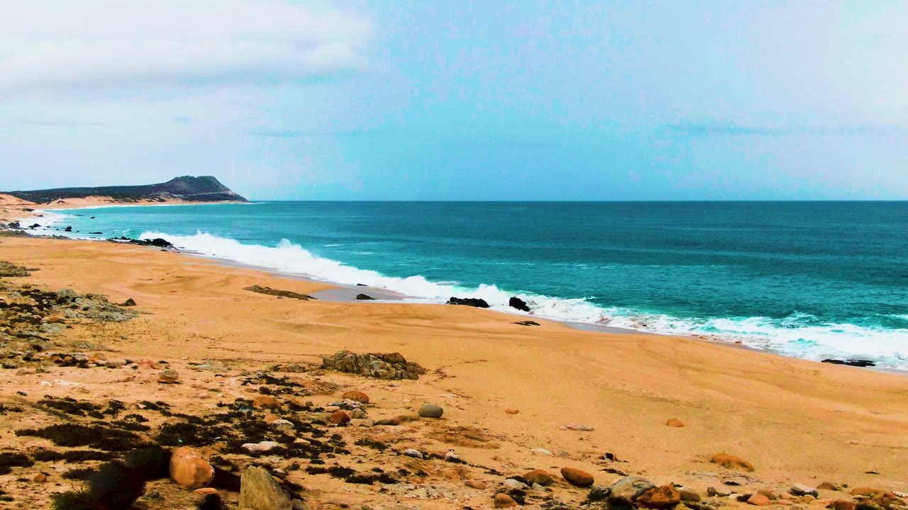 Wide sandy beach with turquoise ocean and white surf
