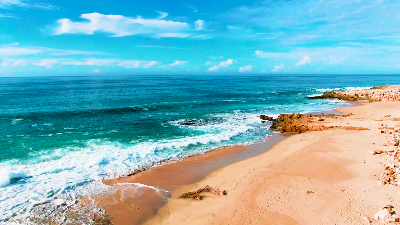 Broad ocean view with surf washing onto a tan beach.