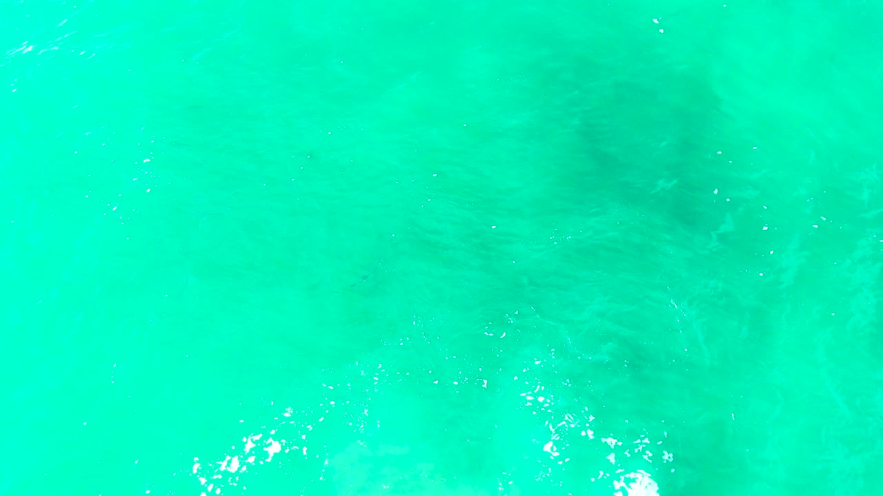 Turquoise water with a faint horizontal change in tone and white foam near the lower edge.