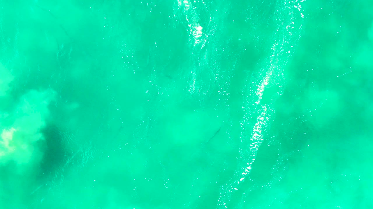 Turquoise ocean surface with foam and a dark underwater shadow near the left edge