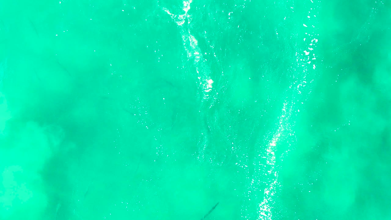 Bright turquoise water with a foamy vertical current line and faint fish.