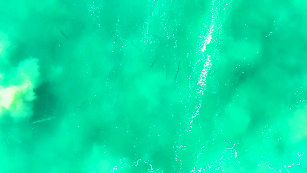 Top-down Punta Buzzards water frame with vertical sun shimmer streaks, soft pale turbulence near the bottom edge, faint fish shapes, and no visible people.