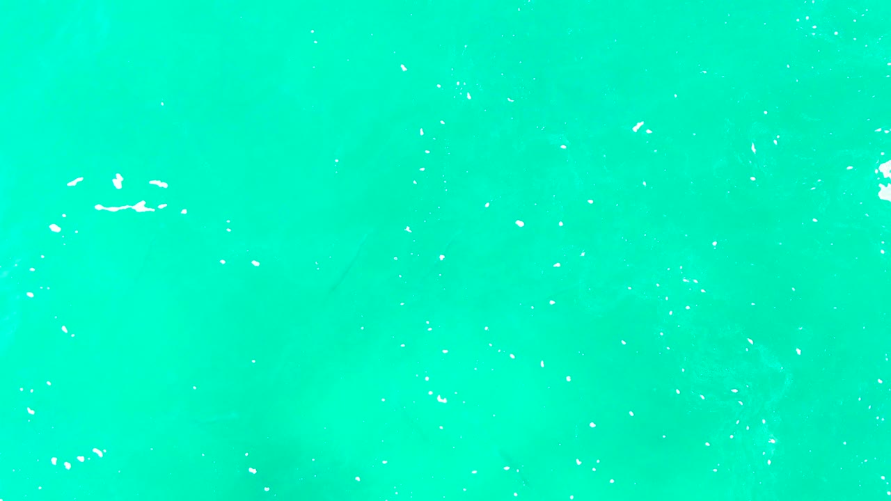 Aerial frame of blue-green ocean surface near Punta Buzzards with sparse white foam marks spread across the water and no visible people.
