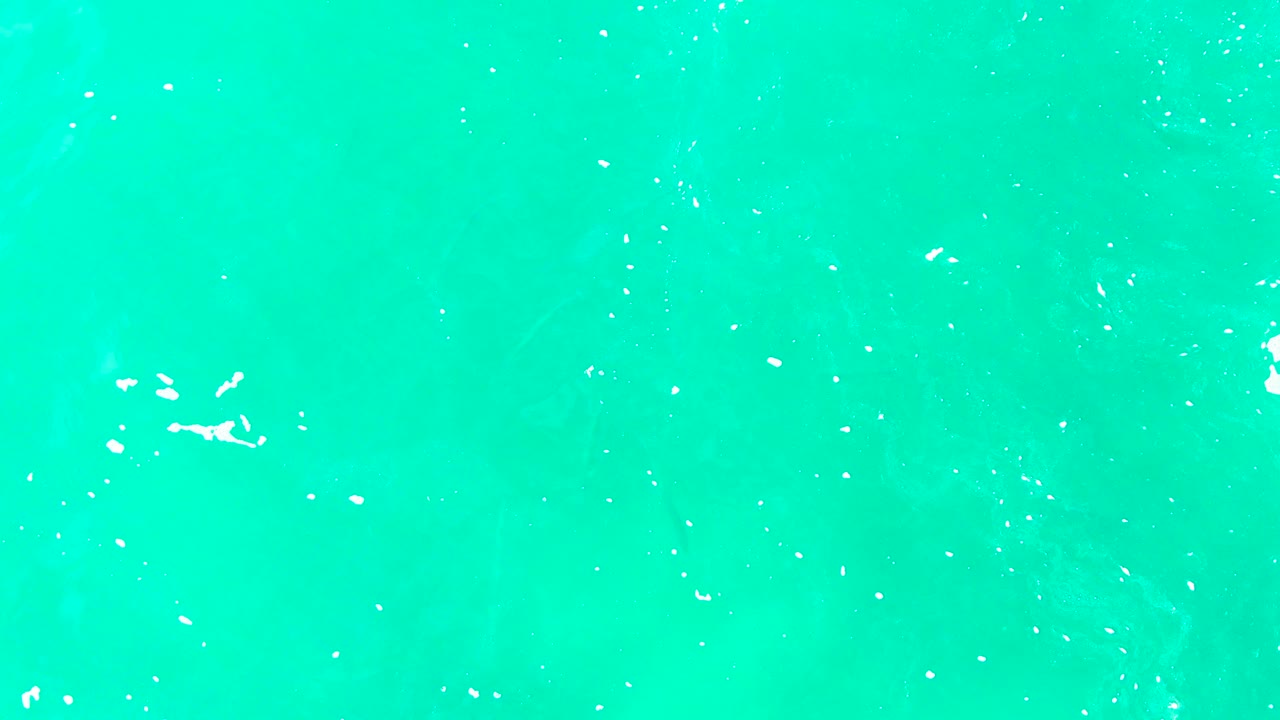 Overhead Punta Buzzards ocean surface with white foam flecks shifted across the upper center of the blue-green water and no visible people.