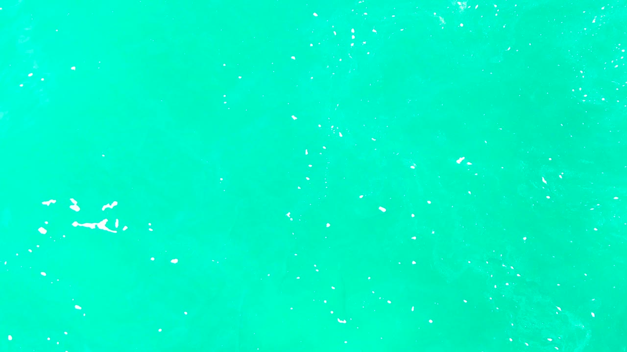 Overhead turquoise sea with scattered white foam.