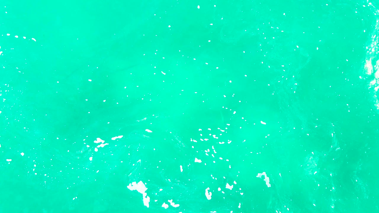 Turquoise ocean surface with small white foam patches.