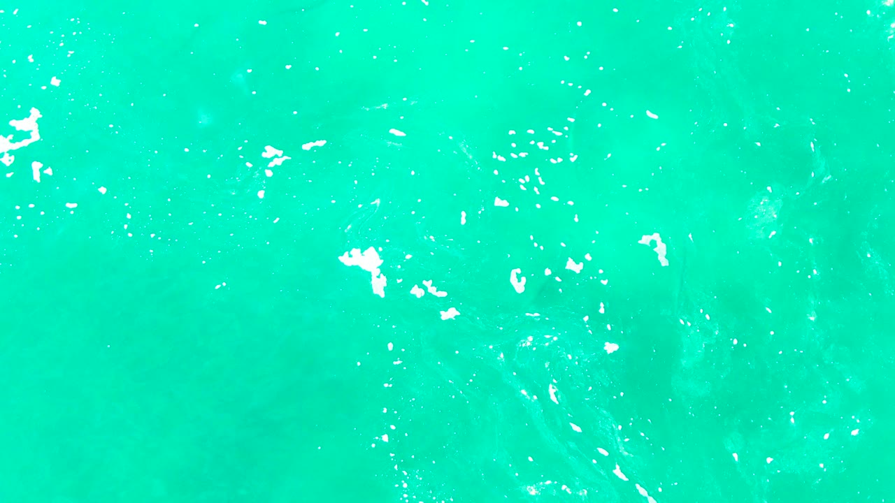 Turquoise sea surface at Punta Buzzards with white sun glints and ripple lines concentrated around the center, with no visible people.
