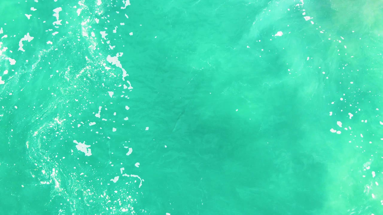 Teal water surface with bubbles and foam