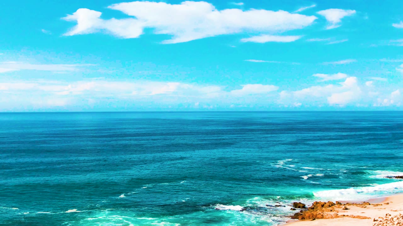 Ocean and turquoise surf bands with a small section of beach at the lower right.