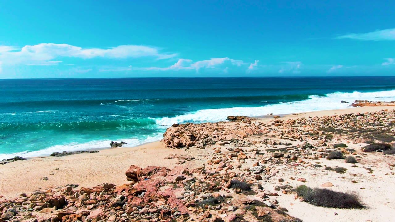 Rocky beach and turquoise waves under a blue sky