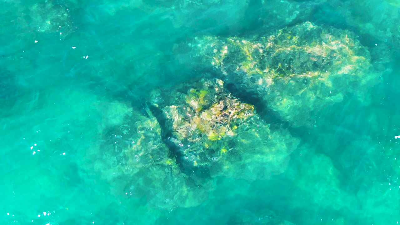 Pale submerged rocks under calm turquoise water.