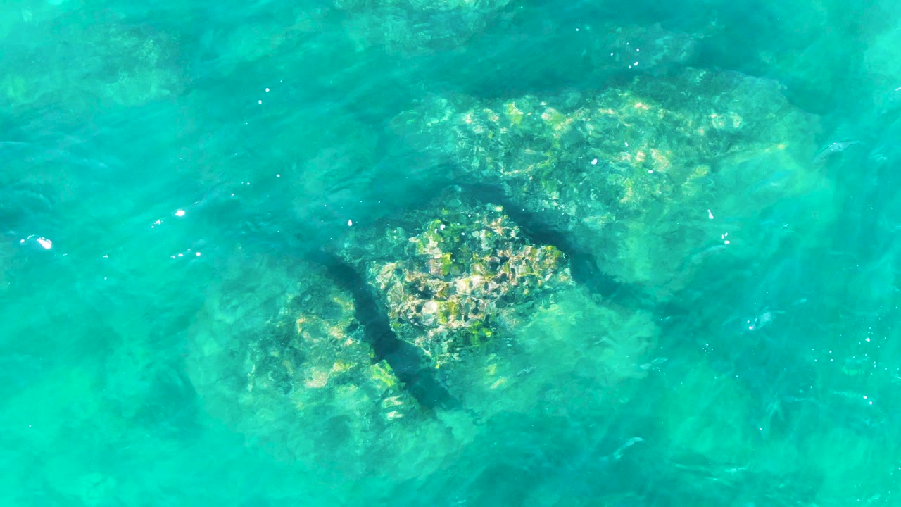Large underwater rocks beneath rippled water