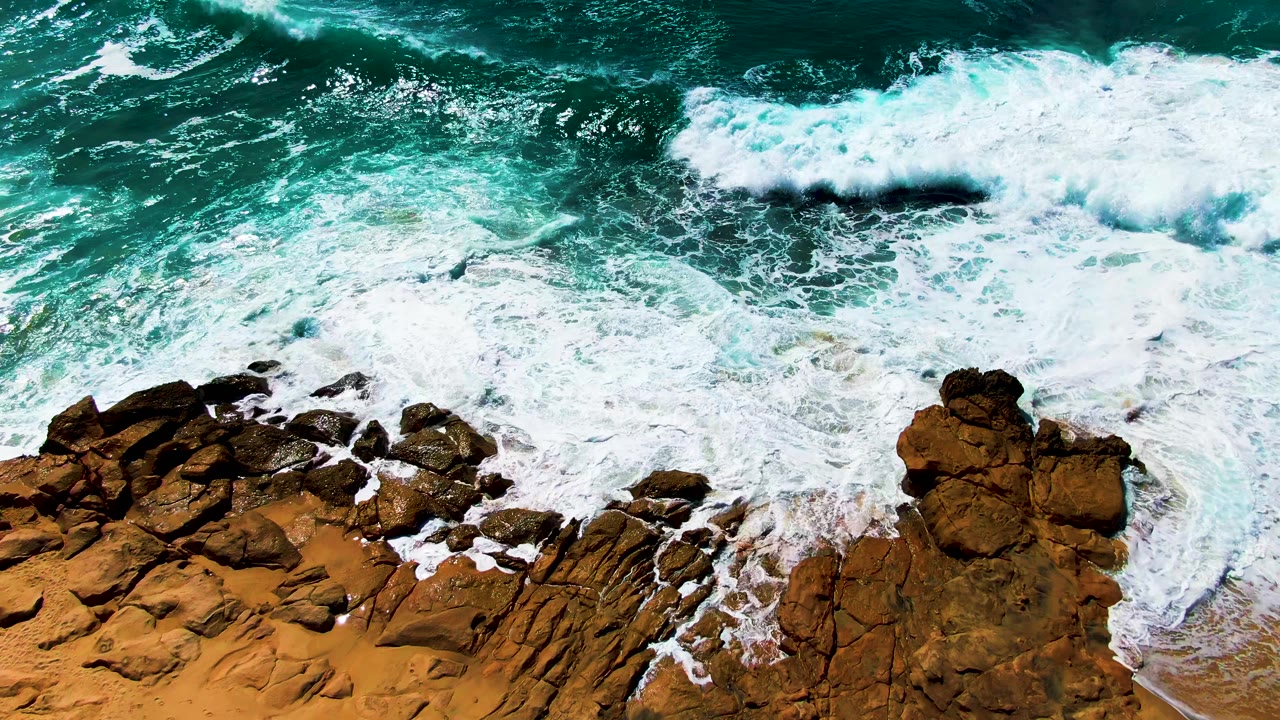 Foamy wave wash curling around a rocky outcrop