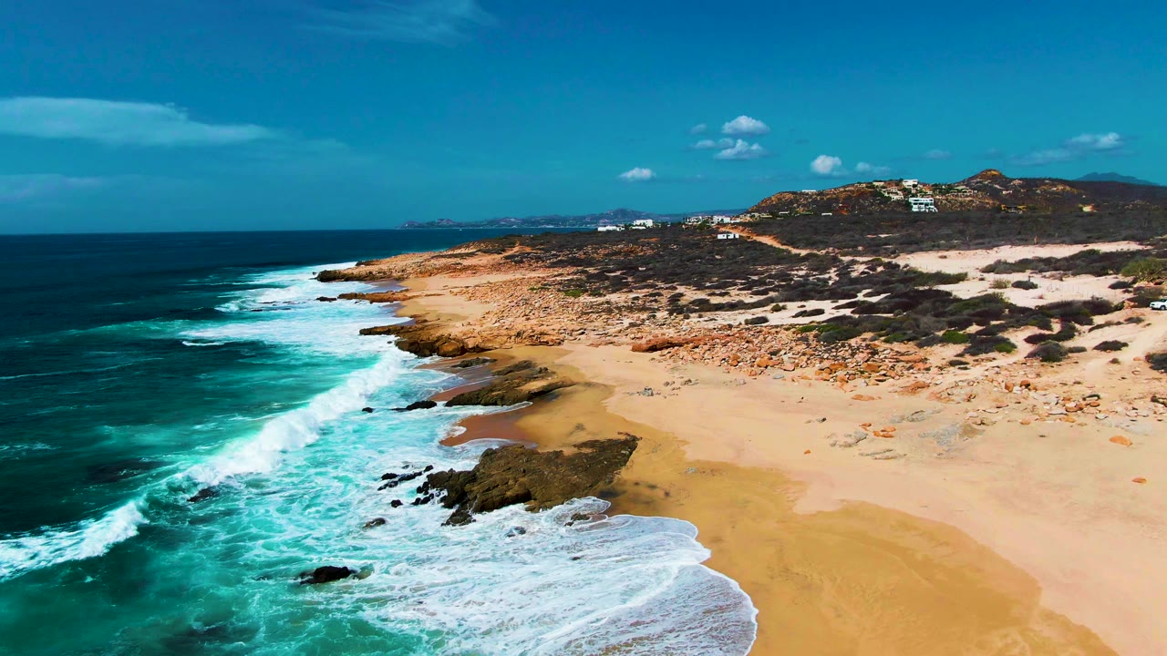 Aerial coastline with foamy surf and rocky shore.