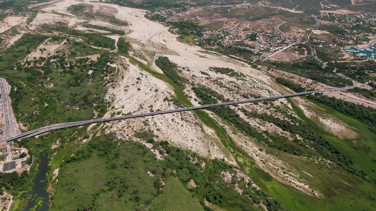 Overhead landscape with bridge, dry riverbed, roads, and a green wash.