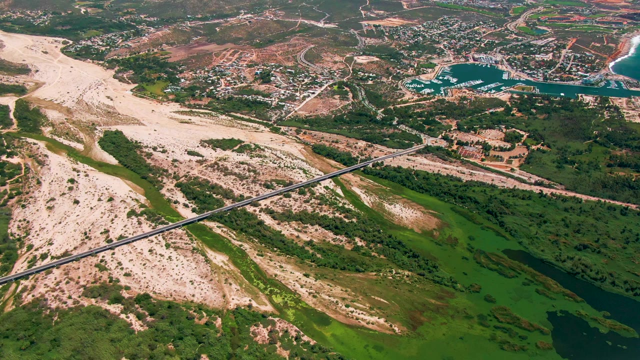 Third frame shows San Jose Del Cabo from above with pale sand flats on the left, a diagonal bridge across the lower frame, green vegetation around dark water, blue shoreline water at right, and no visible people.